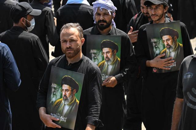 Shia Muslims hold portraits of Iran's supreme leader Mojtaba Khamenei (R) and late supreme leader Ayatollah Ali Khamenei as they take part in a procession on the ninth-day of the Islamic holy month of Muharram in Islamabad on June 25, 2026. (Photo by Aamir QURESHI / AFP)