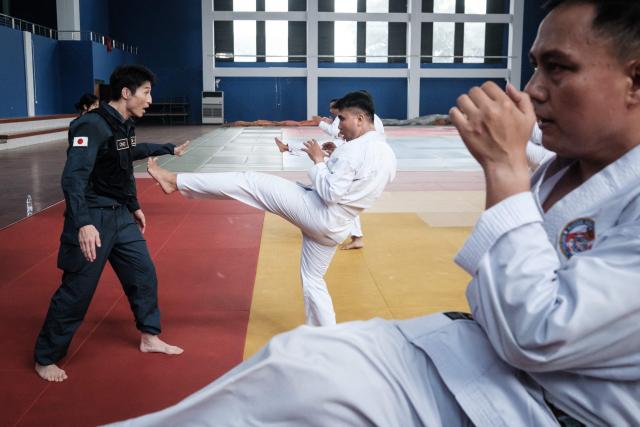 A maritime law enforcement instructor from the Japan Coast Guard's Mobile Cooperation Team (MCT) teaches arrest and restraint techniques adapted from Japanese martial arts to officers of the Indonesian Maritime Security Agency (BAKAMLA) during a final training session ahead of their instructor certification examination at Gedung Judo in Jakarta on June 25, 2026. The Japan Coast Guard's Mobile Cooperation Team (MCT) provides capacity-building assistance to foreign coast guard agencies in 23 countries to help strengthen maritime security and ensure the safety of international sea lanes. (Photo by Yasuyoshi Chiba / AFP)
