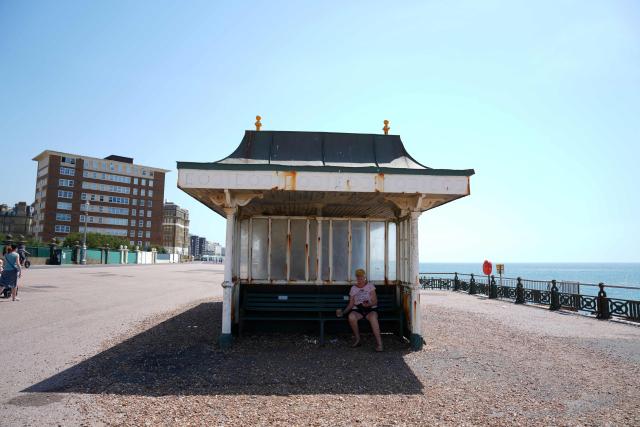 A person shelters from the heat of he sun by sitting in the shade of a beach shelter in Hove, on the south coast of England on June 25, 2026, during a heatwave. The UK recorded its hottest ever June temperature on June 24 with the mercury rising to 36.1C in southern England, breaking the previous record of 35.6C set in 1976. (Photo by CARLOS JASSO / AFP)