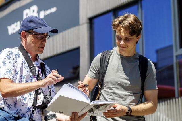 McLaren's Australian driver Oscar Piastri (R) signs an autograph for a fan upon arrival at the Red Bull Ring race track in Spielberg, Austria on June 25, 2026, ahead of the Formula One Austrian Grand Prix. (Photo by ERWIN SCHERIAU / APA / AFP) / Austria OUT
