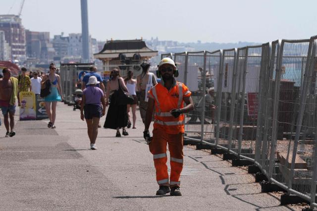 Workers working on the coastal protection scheme to improve the beach groynes, walk by the beach in the sun in Hove, on the south coast of England on June 25, 2026, during a heatwave. The UK recorded its hottest ever June temperature on June 24 with the mercury rising to 36.1C in southern England, breaking the previous record of 35.6C set in 1976. (Photo by CARLOS JASSO / AFP)