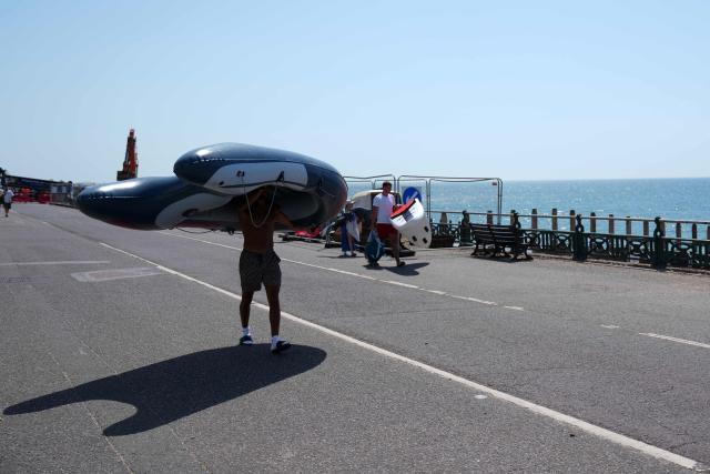 People carry inflatable boats and paddleboards as they arrive at the beach in Hove, on the south coast of England on June 25, 2026, during a heatwave. The UK recorded its hottest ever June temperature on June 24 with the mercury rising to 36.1C in southern England, breaking the previous record of 35.6C set in 1976. (Photo by CARLOS JASSO / AFP)