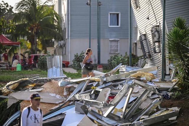 A woman walks past debris from a damaged building following an earthquake in Catia La Mar, La Guaira state, some 30km north-west of Caracas, on June 25, 2026. A twin earthquake that was Venezuela's largest in over a century has killed at least 164 people and destroyed multiple buildings near the capital, where residents searched on June 25 for missing relatives. (Photo by Federico PARRA / AFP)