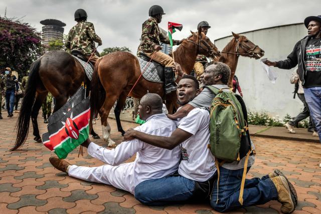 Protesters react as Kenyan police officers on horseback surround them outside Parliament buildings during demonstrations marking the second anniversary of the deadly June 2024 youth-led anti-Finance Bill protests, which saw demonstrators storm Parliament, in Nairobi on June 25, 2026. Kenyan police put on a massive show of force on June 25 in a bid to prevent protests marking two years since a landmark Gen Z uprising. Thousands of Kenyans took to the streets in June 2024 against economic hardship and corruption, eventually storming parliament to force the cancellation of new taxes. (Photo by Luis TATO / AFP)