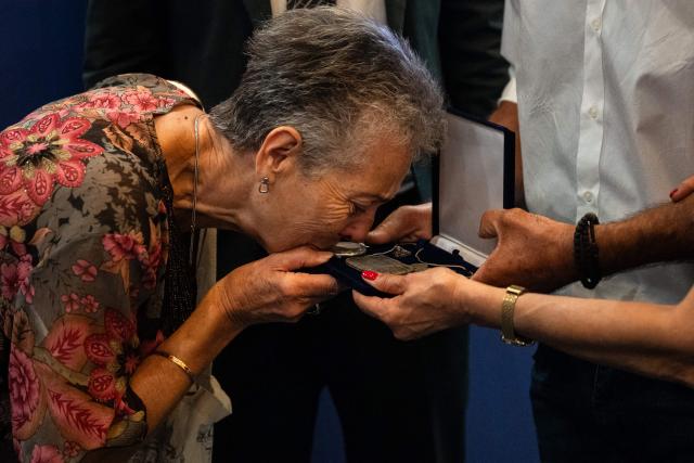 A relative of Dimitris Vafeiadis kisses his personal belongings during a ceremony for the return of personal belongings of Greek prisoners from Nazi forced labor camps to their families, held as part of the international StolenMemory campaign, at the Ministry of Foreign Affairs in Athens on June 25, 2026. (Photo by Angelos TZORTZINIS / AFP)