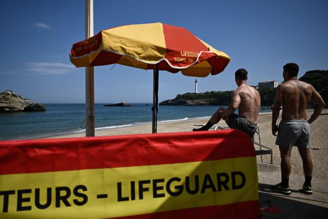Two men stand near a lifeguard post at the Miramar beach as it was closed after a section of a cliff collapsed, killing one woman and leaving a diver missing, in Biarritz, south-western France, on June 25, 2026. The collapse came at around 8:20 pm (1820 GMT) near the Miramar beach, which was packed with swimmers seeking respite from a punishing heatwave. (Photo by Philippe LOPEZ / AFP)