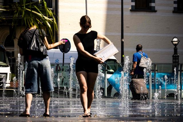 People try to cool off in a fountain in the centre of Tilburg on June 25, 2026 during a heatwave in Europe. A code orange warning is in effect in the central and southern Netherlands due to extreme heat. At least 101 million Europeans were expected to experience temperatures of over 35C on June 25, 2026, in a punishing and increasingly deadly heatwave hotter than weather in parts of Africa. (Photo by ROB ENGELAAR / ANP / AFP) / Netherlands OUT
