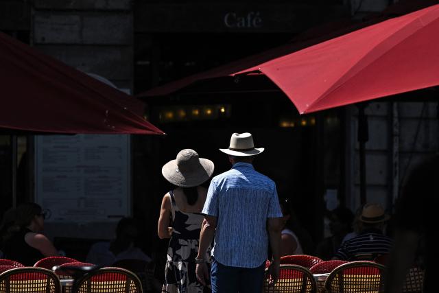 A couple wearing hats to shelter from the sun walk into a restaurant during a heatwave in Bordeaux, southwestern France on June 25, 2026. At least 101 million Europeans were expected to experience temperatures of over 35C on June 25, 2026, in a punishing and increasingly deadly heatwave hotter than weather in parts of Africa. France and Spain, among the countries worst hit, began counting the toll from the extreme temperatures, with children among the victims. (Photo by Christophe ARCHAMBAULT / AFP)