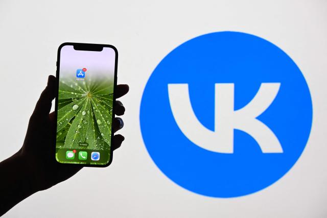 This illustration photograph shows the logo of Russian social media platform VK displayed on a TV screen and AppStore logo displayed on a smartphone in Moscow on June 25, 2026. Apple has removed VKontakte, one of Russia's largest social networks, from its App Store, the Russian company said on June 25, 2026, with the Kremlin calling for an explanation from the California-based tech giant. VKontakte (VK) was launched in 2006 as Russia's answer to Facebook and has since grown to become one of the most popular websites and social media platforms in the country. (Photo by Igor IVANKO / AFP)