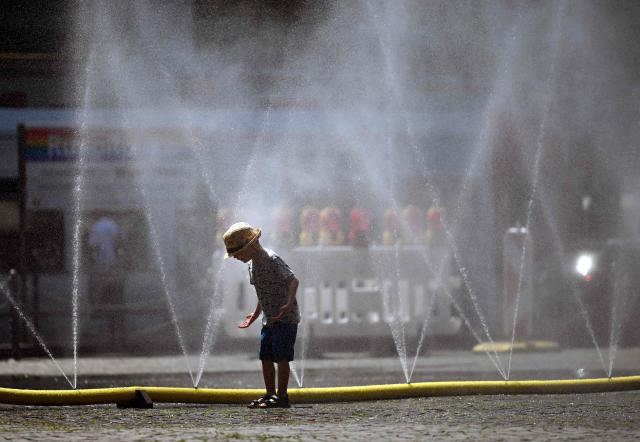 A young boy stands next to water hoses spilling water to provide relief from the summer heat as part of Colognes climate adaptation measures in Cologne, western Germany on June 25, 2026 during a heatwave in Europe. A heatwave sweeping Europe was starting to peak in Germany on June 25, 2026, with several open-air events cancelled and temperatures expected to top 40C through the weekend. Large parts of the country are already under "severe to extreme heat stress" with temperatures soaring to around 37C, the German Weather Service (DWD) said. (Photo by Ina FASSBENDER / AFP)