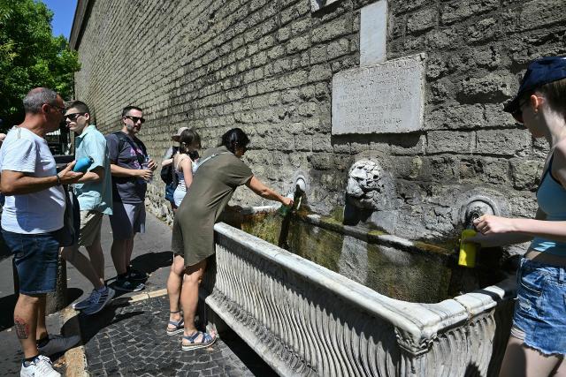 People queue to fill their bottles with water at a public fountain during a heatwave, in Rome on June 25, 2026. (Photo by Andreas SOLARO / AFP)