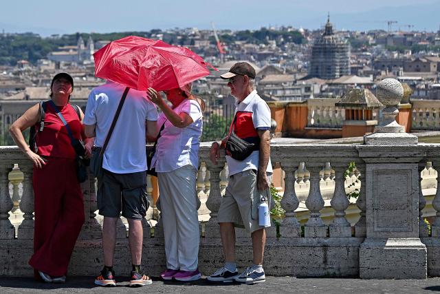 Tourists hold an umbrella to shield themselves from the sun in front of the panoramic view from the Paola Fountain in Rome, on June 25, 2026. (Photo by Andreas SOLARO / AFP)