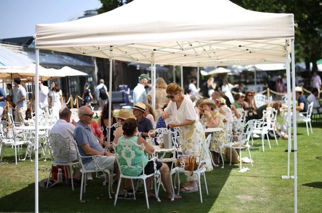 Tennis fans shelter from the heat of the sun, ahead of play at the Giorgio Armani Tennis Classic tournament at the Hurlingham Club in London on June 25, 2026. (Photo by Henry Nicholls / AFP)