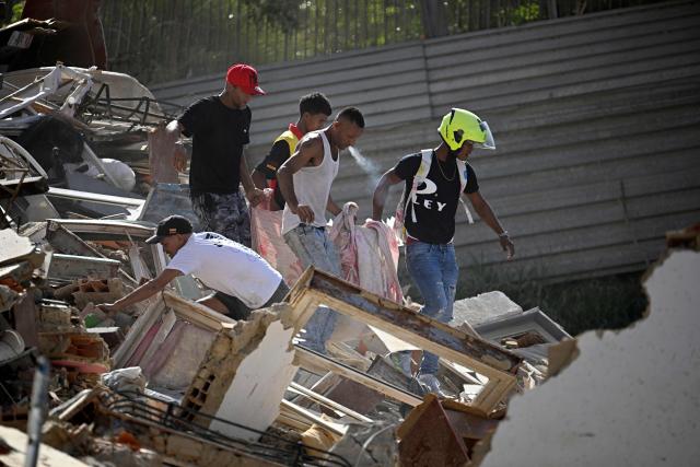 Men carry a body through the rubble of a collapsed building following an earthquake in Catia La Mar, La Guaira state, about 30 km northwest of Caracas, on June 25, 2026. A twin earthquake that was Venezuela's largest in over a century has killed at least 164 people and destroyed multiple buildings near the capital, where residents searched on June 25 for missing relatives. (Photo by Federico PARRA / AFP)