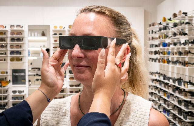A woman tries on eclipse viewing glasses certified with the ISO 12312-2:2015 international safety standard which specifies requirements for direct observation of the sun, at an optician's shop in Palma de Mallorca on June 25, 2026. According to Spain's National Astronomical Observatory, during the evening of Wednesday, August 12, 2026, a total solar eclipse will be visible from the Iberian Peninsula, marking the first such event in over a century. The path of totality of this eclipse will cross Spain from west to east and will pass throught numerous provincial capitals from La Coruna to Palma including Oviedo, Leon, Bilbao, Zaragoza, and Valencia. (Photo by Jaime REINA / AFP)