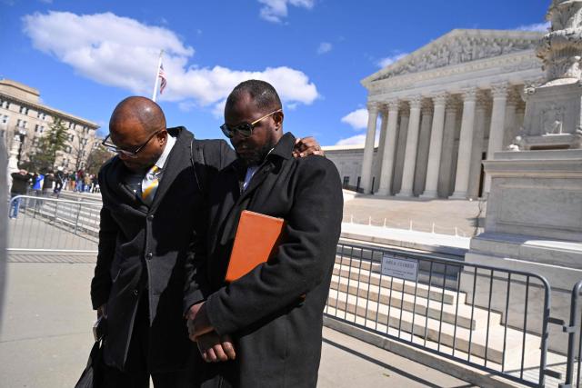 (FILES) Viles Dorsainvil (R), Executive Director of the Haitian Support Center, and Associate Pastor Brandon Peterson of Greater Grace Temple in Springfield, Ohio, listen to a prayer outside the US Supreme Court in Washington, DC, on March 17, 2026. The US Supreme Court on June 25, 2026, backed a Trump administration move to strip deportation protections from some 350,000 Haitians in the United States and 6,000 Syrians. The conservative-dominated court, in a 6-3 decision, said the Department of Homeland Security's decision to end Temporary Protected Status (TPS) for the Haitian and Syrian immigrants was not subject to judicial review. (Photo by ROBERTO SCHMIDT / AFP)