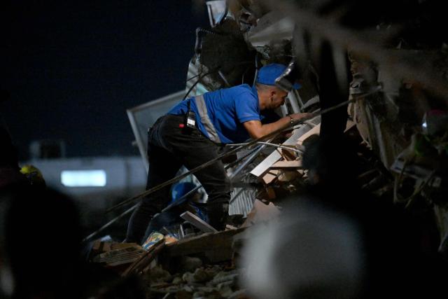 A rescuer works at the site of a collapsed building following an earthquake in Caracas on June 24, 2026. A twin earthquake that was Venezuela's largest in over a century has killed at least 164 people and destroyed multiple buildings near the capital, where residents searched on June 25 for missing relatives. (Photo by Juan BARRETO / AFP)