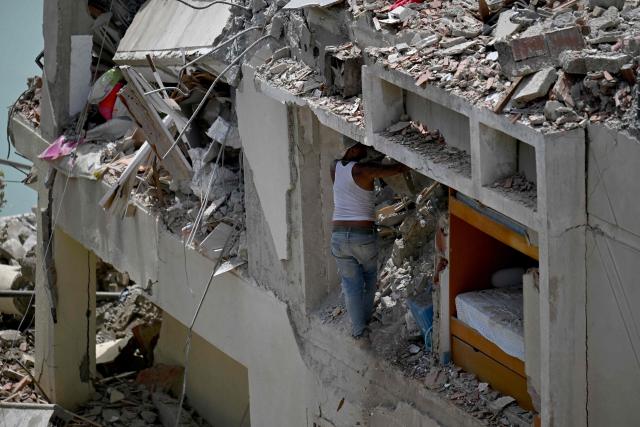 A man searches through the rubble of a collapsed building as he tries to recover belongings following an earthquake in Catia La Mar, La Guaira state, about 30 km northwest of Caracas, on June 25, 2026. A twin earthquake that was Venezuela's largest in over a century has killed at least 164 people and destroyed multiple buildings near the capital, where residents searched on June 25 for missing relatives. (Photo by Juan BARRETO / AFP)
