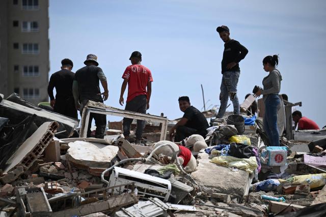 Residents search through the rubble of collapsed buildings as they try to recover belongings following an earthquake in Catia La Mar, La Guaira state, about 30 km northwest of Caracas, on June 25, 2026. A twin earthquake that was Venezuela's largest in over a century has killed at least 164 people and destroyed multiple buildings near the capital, where residents searched on June 25 for missing relatives. (Photo by Juan BARRETO / AFP)
