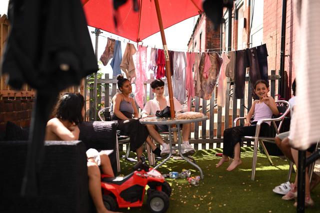 A family sit in the shade of the sun in their front garden in an eastern area of Leeds, northern England on June 25, 2026. The UK recorded its hottest ever June temperature on June 24 with the mercury rising to 36.1C in southern England, breaking the previous record of 35.6C set in 1976. (Photo by Oli SCARFF / AFP)