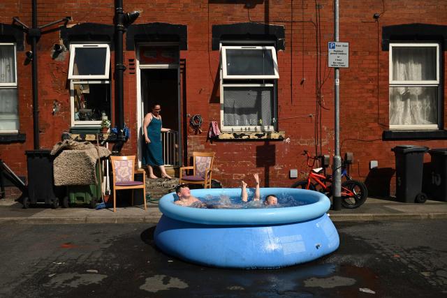 TOPSHOT - Six-year-old Cody and nine-year-old Jason are watched by their mother as they play in a paddling pool in the street outside their home, in an eastern area of Leeds, northern England on June 25, 2026. The UK recorded its hottest ever June temperature on June 24 with the mercury rising to 36.1C in southern England, breaking the previous record of 35.6C set in 1976. (Photo by Oli SCARFF / AFP)