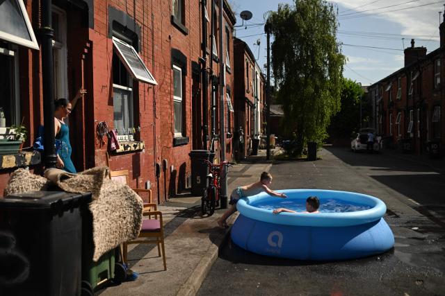 A family take advantage of the hot and sunny weather to wash rugs in the street by their home, in an eastern area of Leeds, northern England on June 25, 2026. The UK recorded its hottest ever June temperature on June 24 with the mercury rising to 36.1C in southern England, breaking the previous record of 35.6C set in 1976. (Photo by Oli SCARFF / AFP)