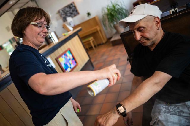 A volunteer at a community centre of the Berliner Stadt Mission (Berlin City Mission) applies sunscreen on the arms of a guest in Berlin on June 25, 2026, as the capital braces for temperatures hovering around 40 degrees centigrade over the weekend. (Photo by John MACDOUGALL / AFP)