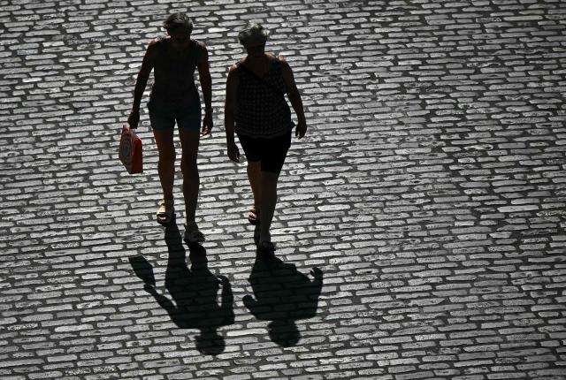 People are silhouetted as they walk in the sun, in Guildford, on June 25, 2026, during a heatwave. The UK recorded its hottest ever June temperature on June 24 with the mercury rising to 36.1C in southern England, breaking the previous record of 35.6C set in 1976. (Photo by JUSTIN TALLIS / AFP)