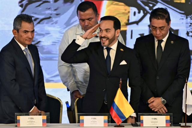 Colombia's President-elect Abelardo de la Espriella (C), accompanied by National Electoral Council (CNE) magistrate Alfonso Campo (L) and CNE President Cristian Quiroz (R), salutes before receiving his official credential at the National Registry of Civil Status headquarters in Bogota on June 25, 2026.  (Photo by Luis ACOSTA / AFP)