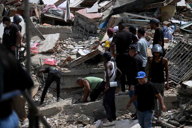 Residents search for victims through the rubble of a collapsed building in Catia La Mar, La Guaira state, about 30 km northwest of Caracas, on June 25, 2026, following an earthquake. A twin earthquake that was Venezuela's largest in over a century has killed at least 164 people and destroyed multiple buildings near the capital, where residents searched on June 25 for missing relatives. (Photo by Juan BARRETO / AFP)