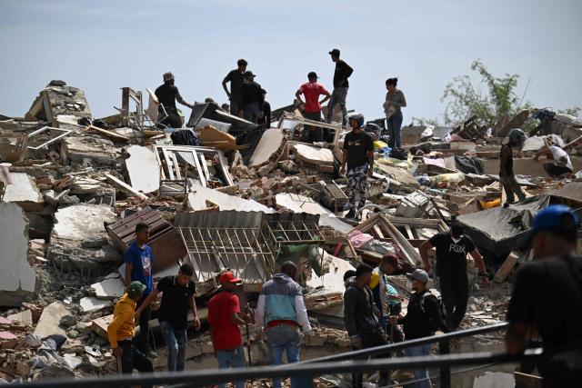 Residents search for victims through the rubble of a collapsed building in Catia La Mar, La Guaira state, about 30 km northwest of Caracas, on June 25, 2026, following an earthquake. A twin earthquake that was Venezuela's largest in over a century has killed at least 164 people and destroyed multiple buildings near the capital, where residents searched on June 25 for missing relatives. (Photo by Juan BARRETO / AFP)