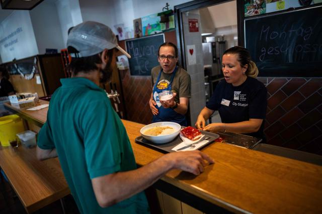 Volunteers at a community centre of the Berliner Stadt Mission (Berlin City Mission) serve a meal to a homeless man in Berlin on June 25, 2026, as the capital braces for temperatures hovering around 40 degrees centigrade over the weekend. (Photo by John MACDOUGALL / AFP)