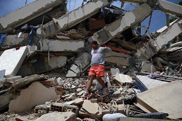 A man moves across the rubble of a collapsed building following an earthquake in Los Corales, La Guaira state, about 38 km northwest of Caracas, on June 25, 2026. A twin earthquake that was Venezuela's largest in over a century has killed at least 188 people and destroyed multiple buildings near the capital, where residents searched on June 25 for missing relatives. (Photo by Federico PARRA / AFP)