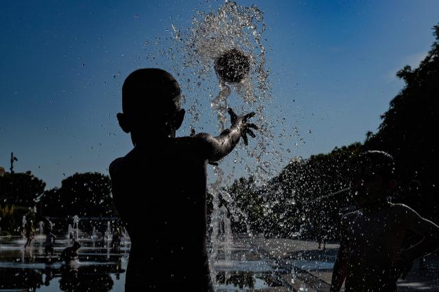 Children play with a ball in a water fountain in Nice, southern France, on June 25, 2026. (Photo by Valery HACHE / AFP)