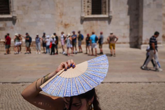 (FILES) A woman shades her head with a fan in front of Jeronimos Monastery in Belem, during a heatwave in Lisbon  on May 27, 2026. (Photo by PATRICIA DE MELO MOREIRA / AFP)