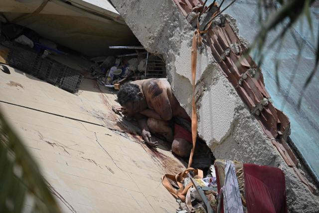 EDITORS NOTE: Graphic content / A man lies dead amid debris inside a partially collapsed building following an earthquake in Los Corales, La Guaira state, about 38 km northwest of Caracas, on June 25, 2026. A twin earthquake that was Venezuela's largest in over a century has killed at least 188 people and destroyed multiple buildings near the capital, where residents searched on June 25 for missing relatives. (Photo by Federico PARRA / AFP)