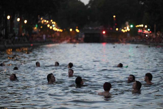 Youths cool down in the waters of the Canal Saint-Martin as France experiences a heatwave, in Paris on June 25, 2026. Due to the ongoing heatwave sweeping across France - the Bassin des Recollets - a portion of the Canal Saint-Martin in the French capital has been opened for swimming from June 17. Authorities said hospitals in Paris and its surrounding region were "saturated" and decided to ban alcohol consumption in the streets and public spaces from June 26 at noon, as well as alcohol sales from 6:00 pm. (Photo by Ludovic MARIN / AFP)