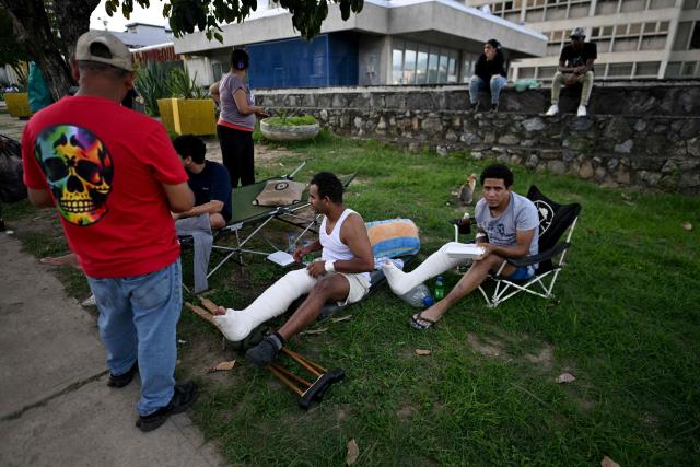 Injured people with leg casts sit outside the Domingo Luciani hospital in Caracas on June 25, 2026, after twin earthquakes struck the Venezuelan capital. The death toll from two powerful earthquakes in Venezuela has risen to at least 188, with more than 1,520 others injured, top lawmaker Jorge Rodriguez said on June 25. Twin quakes, which the US Geological Survey measured at magnitudes 7.2 and 7.5, hit northern Venezuela within a minute of each other on Wednesday night, sending buildings collapsing and trapping many in the rubble. (Photo by Juan BARRETO / AFP)