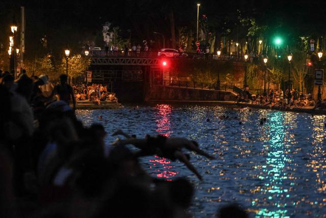 Youths cool down in the waters of the Canal Saint-Martin as France experiences a heatwave, in Paris on June 25, 2026. Due to the ongoing heatwave sweeping across France - the Bassin des Recollets - a portion of the Canal Saint-Martin in the French capital has been opened for swimming from June 17. Authorities said hospitals in Paris and its surrounding region were "saturated" and decided to ban alcohol consumption in the streets and public spaces from June 26 at noon, as well as alcohol sales from 6:00 pm. (Photo by Ludovic MARIN / AFP)