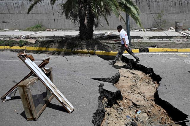 A man walks in a cracked street following a twin earthquake, in Los Corales, La Guaira state, about 38 km northwest of Caracas, on June 25, 2026. The death toll from twin quakes, measured at magnitudes 7.2 and 7.5, has risen to at least 188, with more than 1,520 others injured, top lawmaker Jorge Rodriguez reported, while residents continue searching for missing relatives. (Photo by Federico PARRA / AFP)