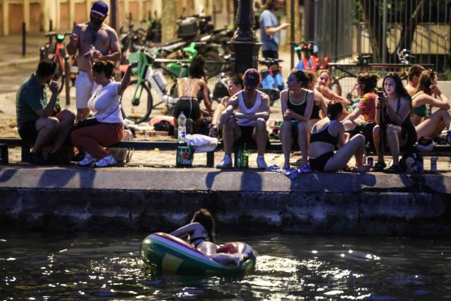 Youths cool down in the waters of the Canal Saint-Martin as France experiences a heatwave, in Paris on June 25, 2026. Due to the ongoing heatwave sweeping across France - the Bassin des Recollets - a portion of the Canal Saint-Martin in the French capital has been opened for swimming from June 17. Authorities said hospitals in Paris and its surrounding region were "saturated" and decided to ban alcohol consumption in the streets and public spaces from June 26 at noon, as well as alcohol sales from 6:00 pm. (Photo by Ludovic MARIN / AFP)