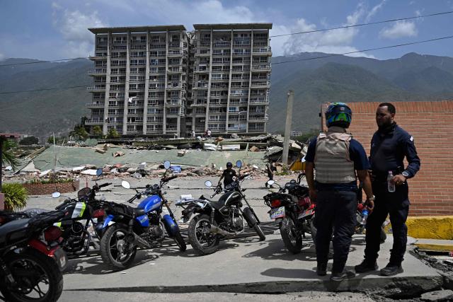 Police members stand nearby a damaged building following a twin earthquake in Los Corales, La Guaira state, about 38 km northwest of Caracas, on June 25, 2026. The death toll from twin quakes, measured at magnitudes 7.2 and 7.5, has risen to at least 188, with more than 1,520 others injured, top lawmaker Jorge Rodriguez reported, while residents continue searching for missing relatives. (Photo by Federico PARRA / AFP)