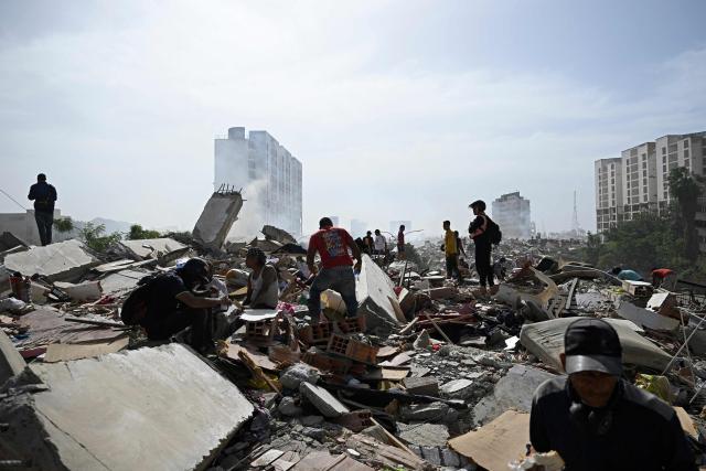Locals walk amid rubble following a twin earthquake in Caraballeda, La Guaira state, about 40 km northeast of Caracas, on June 25, 2026. The death toll from twin quakes, measured at magnitudes 7.2 and 7.5, has risen to at least 188, with more than 1,520 others injured, top lawmaker Jorge Rodriguez reported, while residents continue searching for missing relatives. (Photo by Federico PARRA / AFP)