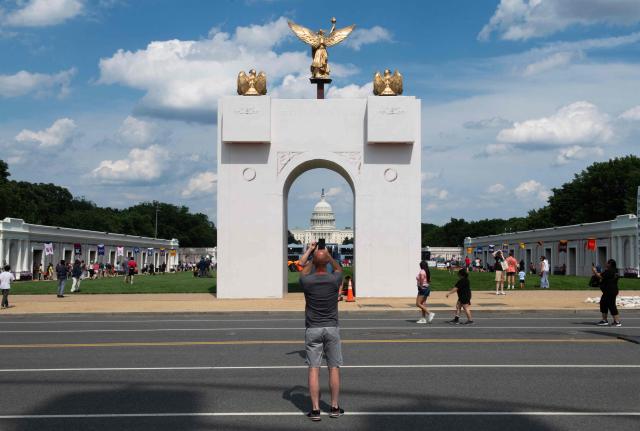 An attendee takes a photo of a replica of the planned Triumphal Arch during the opening day of the "Great American State Fair" on the National Mall in Washington, DC, on June 25, 2026. The "Great American State Fair" will be held from June 25 to July 10, 2026, to celebrate the 250th anniversary of US independence. (Photo by Matthew Hatcher / AFP)