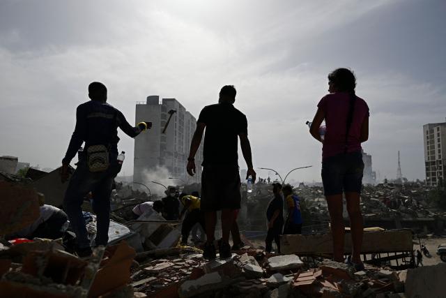 Locals stand amid rubble following a twin earthquake in Caraballeda, La Guaira state, about 40 km northeast of Caracas, on June 25, 2026. The death toll from twin quakes, measured at magnitudes 7.2 and 7.5, has risen to at least 188, with more than 1,520 others injured, top lawmaker Jorge Rodriguez reported, while residents continue searching for missing relatives. (Photo by Federico PARRA / AFP)