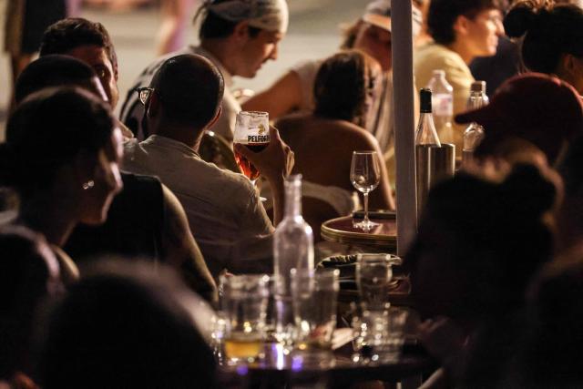 City-dwellers enjoy drinks at a cafe terrace along the Canal Saint-Martin as France experiences a heatwave, in Paris on June 25, 2026. Authorities said hospitals in Paris and its surrounding region were "saturated" and decided to ban alcohol consumption in the streets and public spaces from June 26 at noon, as well as alcohol sales from 6:00 pm. (Photo by Ludovic MARIN / AFP)