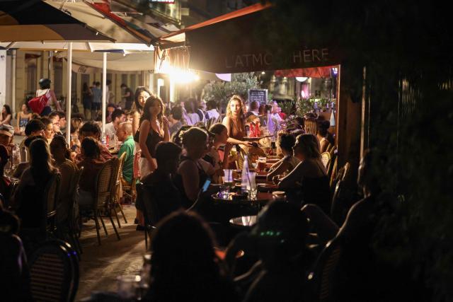 City-dwellers enjoy drinks at a cafe terrace along the Canal Saint-Martin as France experiences a heatwave, in Paris on June 25, 2026. Authorities said hospitals in Paris and its surrounding region were "saturated" and decided to ban alcohol consumption in the streets and public spaces from June 26 at noon, as well as alcohol sales from 6:00 pm. (Photo by Ludovic MARIN / AFP)