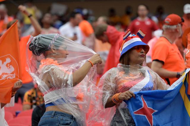 Netherlands' fans protect themselves from the rain ahead the 2026 World Cup Group F football match between Tunisia and the Netherlands at the Kansas City Stadium in Kansas City on June 25, 2026.  (Photo by Juan MABROMATA / AFP)