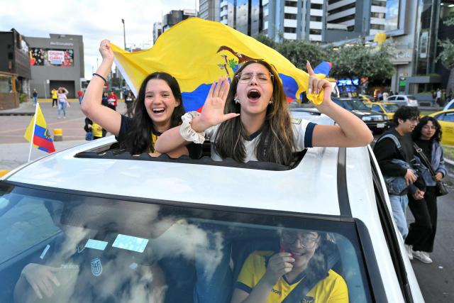 Fans of Ecuador lean through a car sunroof waving a national flag as they celebrate in the street in Quito on June 25, 2026, after their team defeated Germany 2-1 to advance to the last 32 of the FIFA World Cup. (Photo by Rodrigo BUENDIA / AFP)