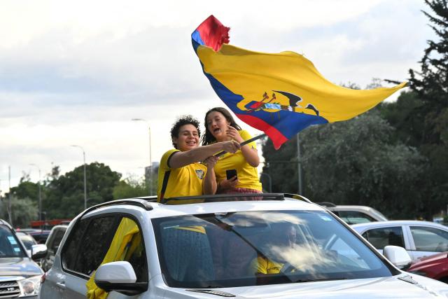 Fans of Ecuador stand through a car sunroof waving a national flag as they celebrate in the street in Quito on June 25, 2026, after their team defeated Germany 2-1 to advance to the last 32 of the FIFA World Cup. (Photo by Rodrigo BUENDIA / AFP)